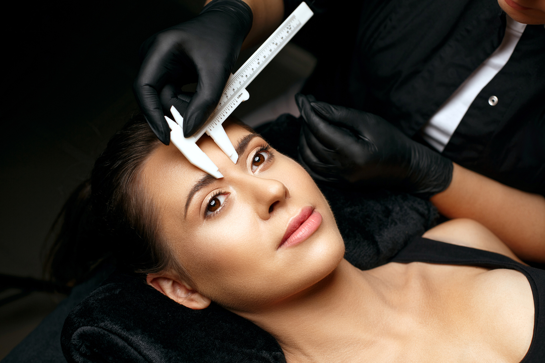 Beautician measuring eyebrows before permanent makeup procedure